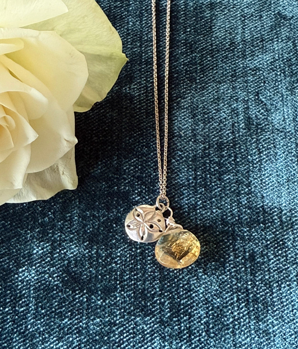 Silver sand dollar pendant by Chorthip featuring a teardrop citrine stone, showing detailed sand dollar design and polished finish.
