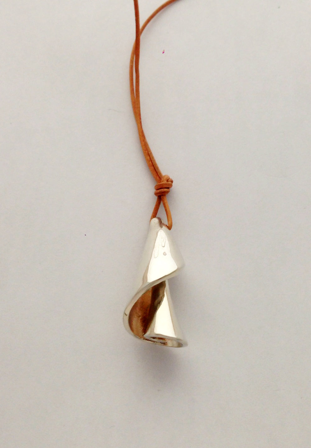 Chorthip Spiral Shell Pendant hanging on a chain, showcasing a detailed, coiled shell design in a polished finish.