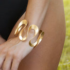 Chorthip Infinity Bangle featuring a sleek, polished gold design with a smooth, continuous loop style on a white background.