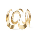 Gold infinity bangle by Chorthip featuring a sleek, open design with smooth curves and polished finish.