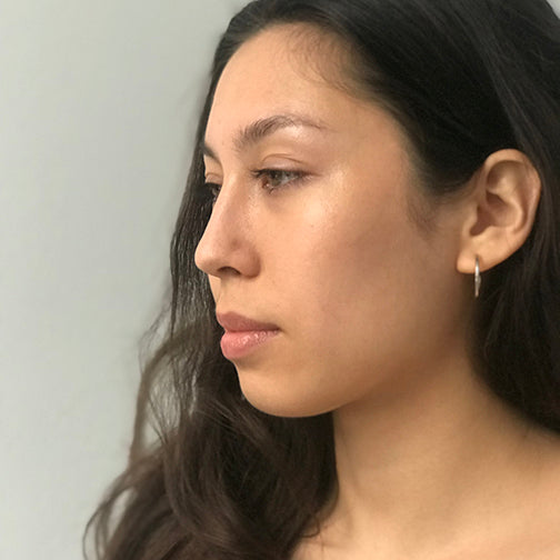 Small raindrop hoop earrings by Chorthip featuring delicate, shiny silver hoops with a smooth, rounded design.