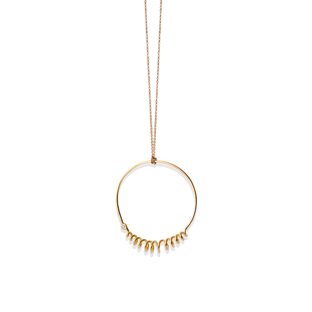 Closeup of Chorthip Helix Circle Pendant showing its spiral design and polished silver finish on a plain background.