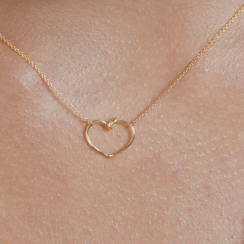Chorthip Heart Knot Pendant featuring a polished silver heart-shaped knot design on a delicate chain.