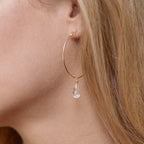 Round knot hoop earrings by Chorthip with white topaz stones, showcasing a stylish and elegant jewelry design.