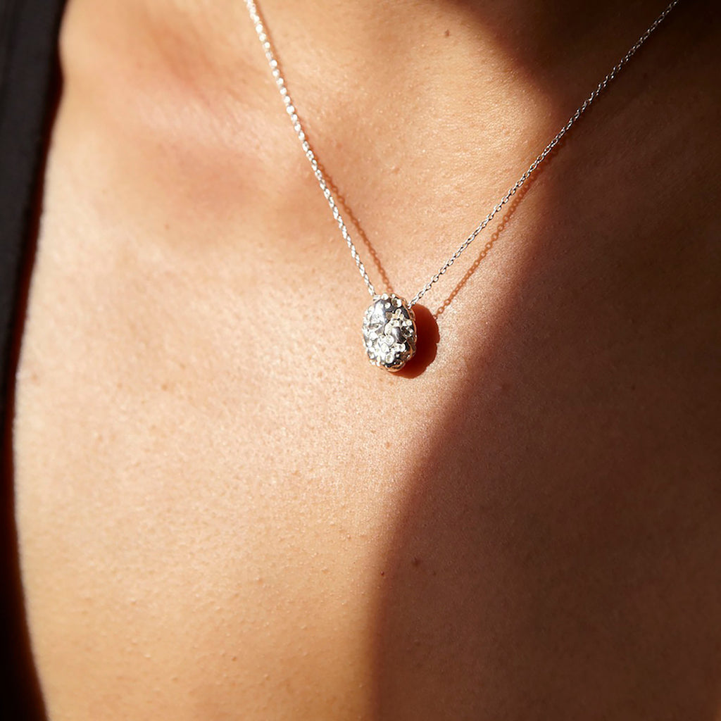 Chorthip lava stone pendant showing a round, textured black volcanic stone jewelry piece on a neutral background.