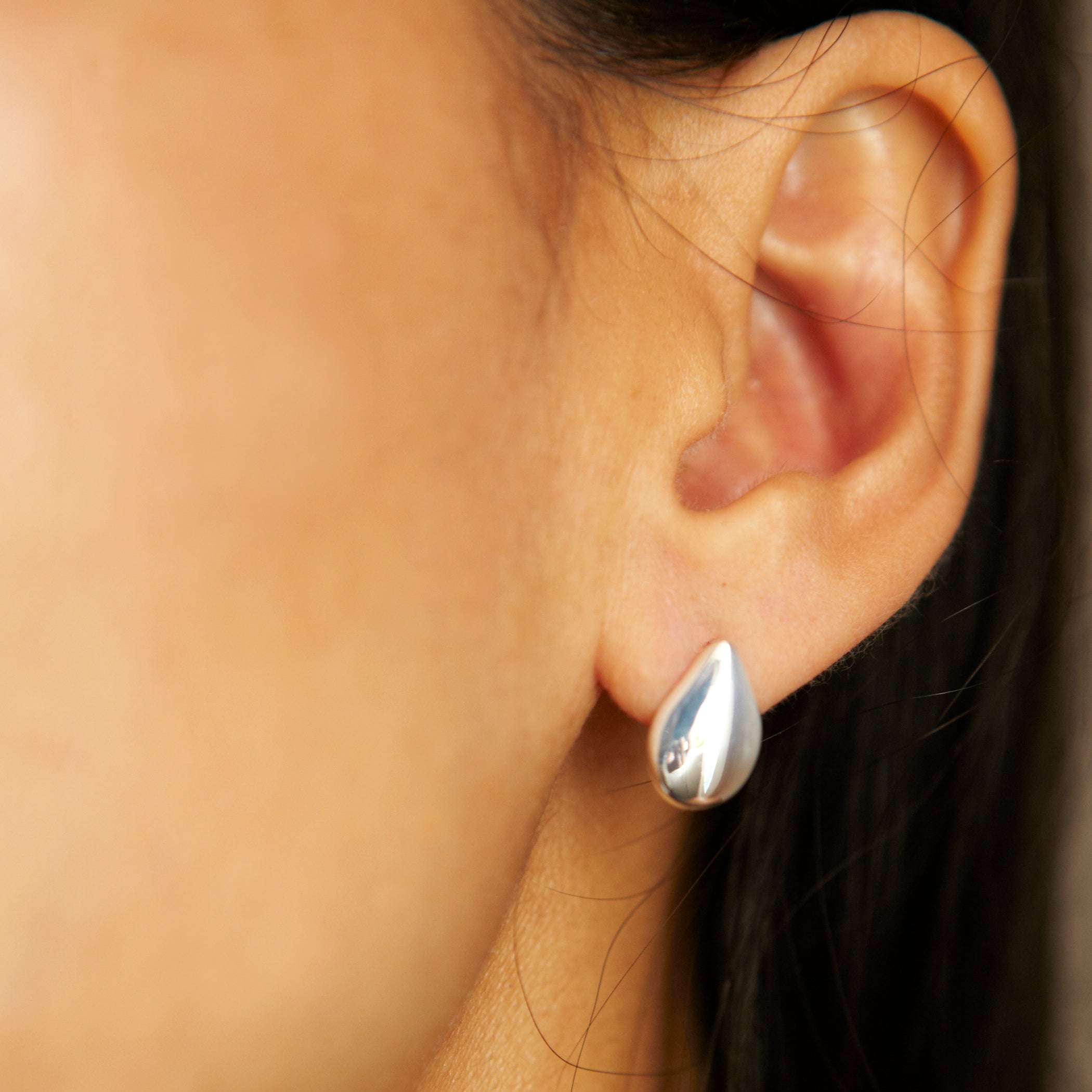 Medium raindrop earrings by Chorthip featuring silver button design, hanging from a delicate hook.
