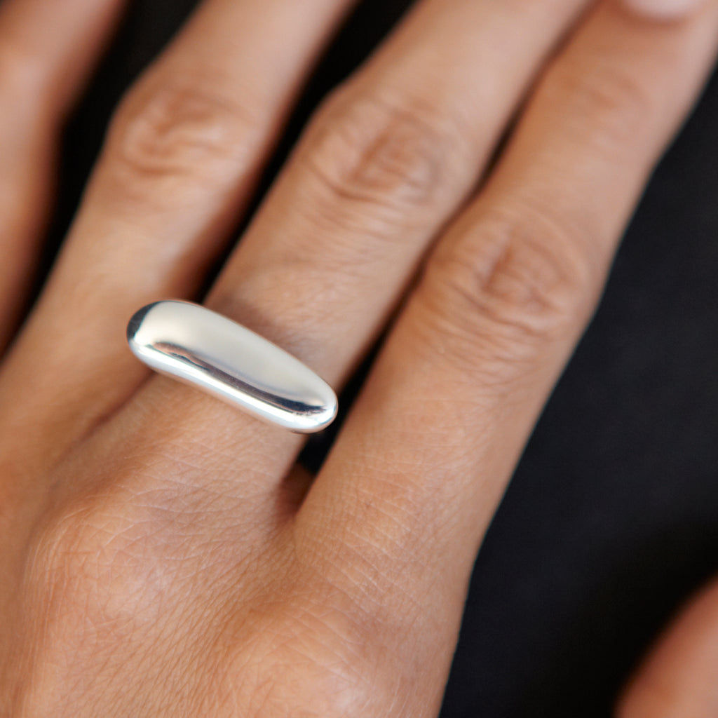 Elongated Pebble Ring by Chorthip featuring a sleek, textured design with smooth, rounded pebble details on a silver band.