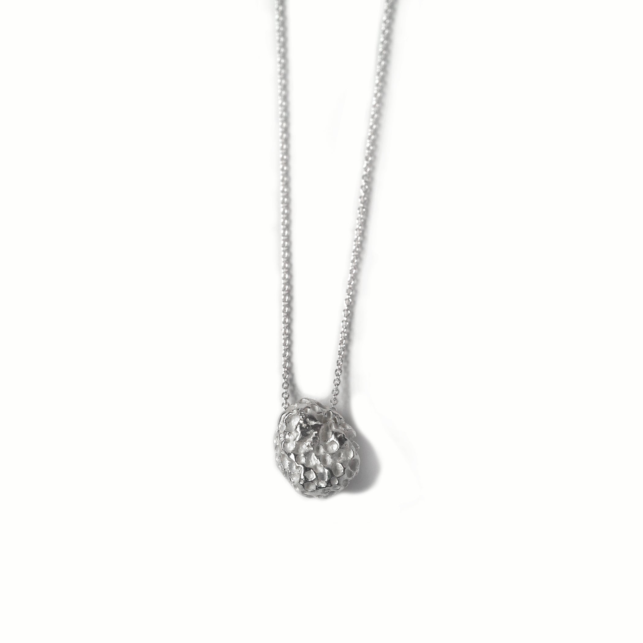 Chorthip lava stone pendant hanging on a chain, showcasing its textured, volcanic surface and dark, earthy tones.