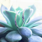 Small raindrop hoop earrings by Chorthip featuring delicate, shiny metal hoops with a smooth raindrop design.